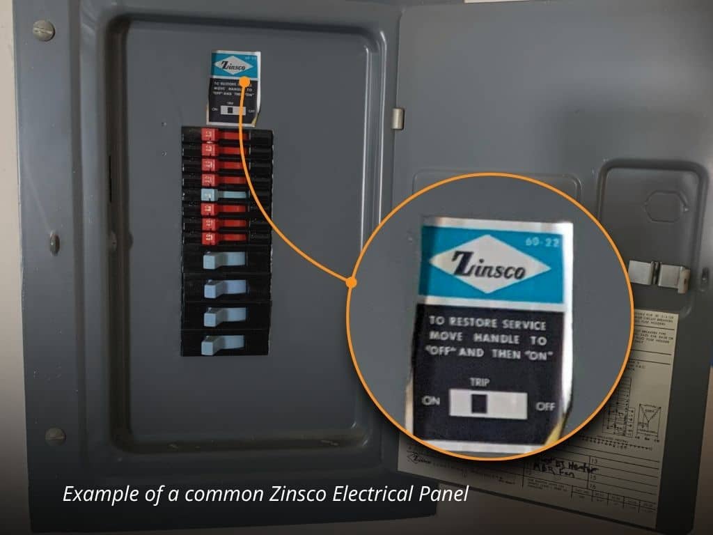 Open Zinsco electrical panel showing the blue Zinsco label and red breaker handles in an older home